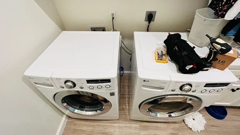 LG front-load washer and dryer with a technician's tool bag during a repair visit