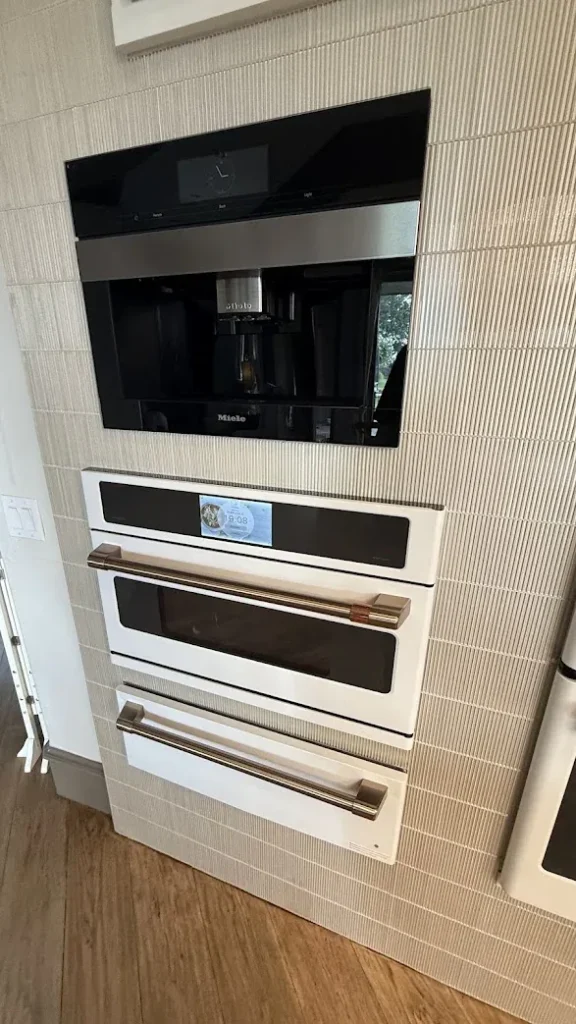 Appliance Repair Edmond, OK 5 Built-in coffee system above two white wall ovens with brass handles