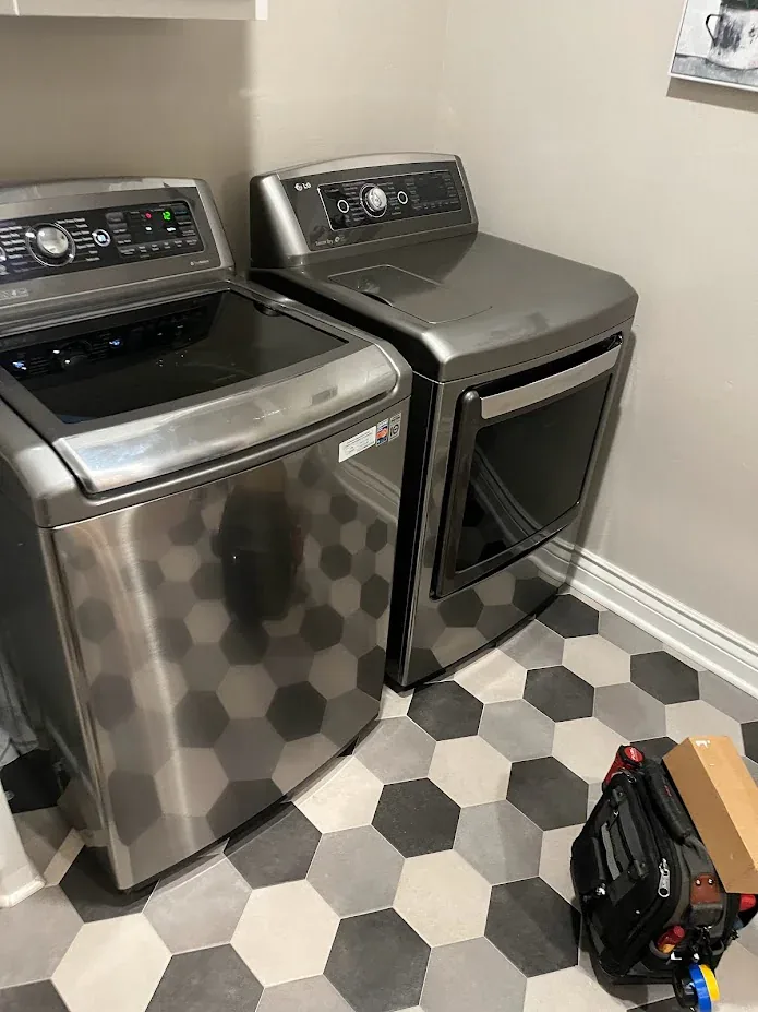 Top-load washer and matching dryer in a laundry room with a hexagon tile floor