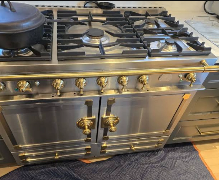Stainless La Cornue-style range with brass knobs and a brass rail