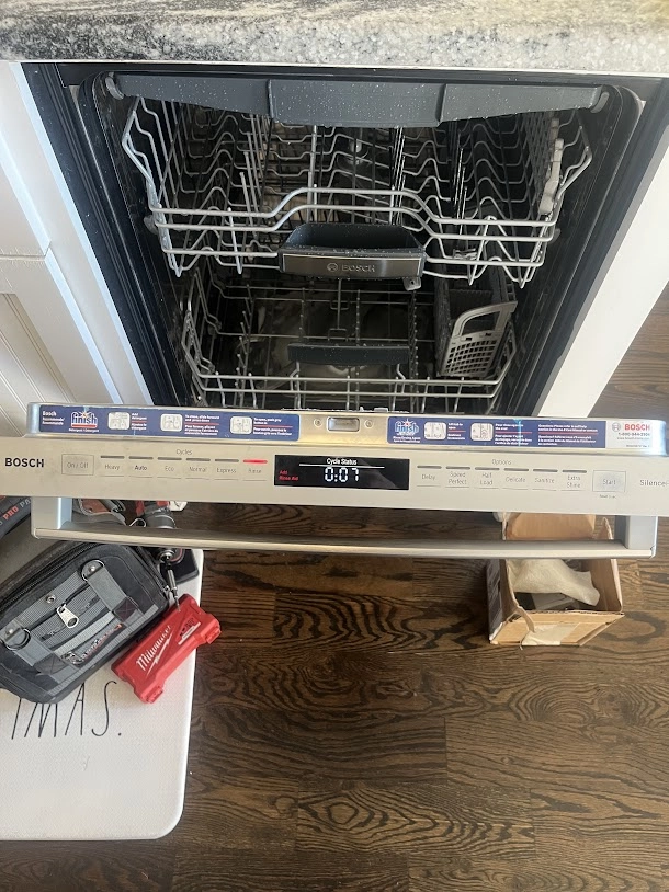 Open Bosch dishwasher with front panel lowered for service.