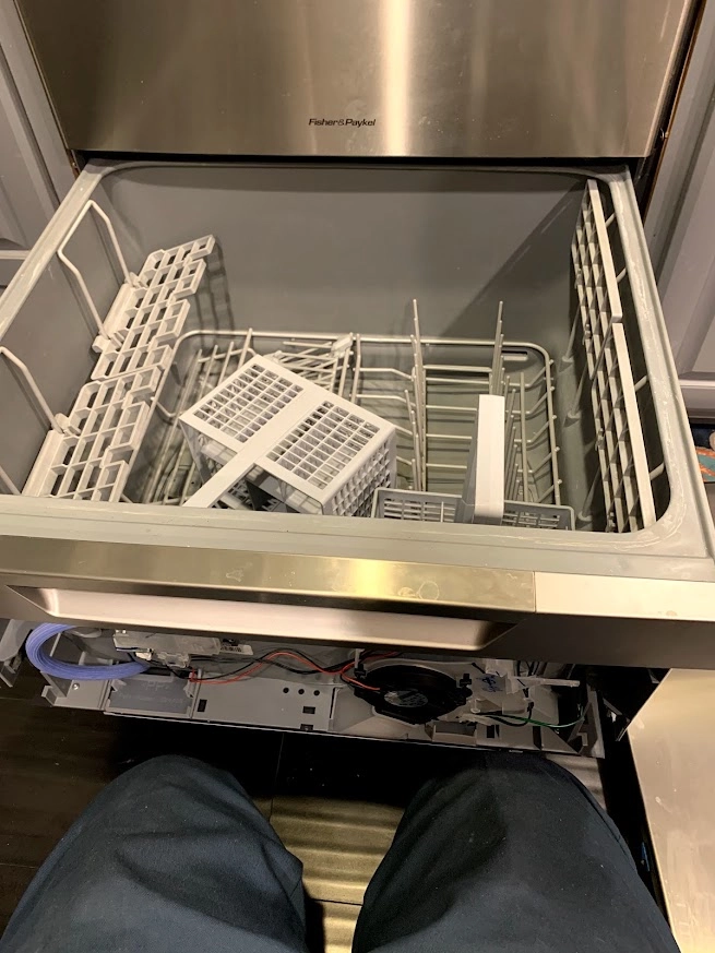 Open Fisher and Paykel dish drawer with racks and front panel exposed.