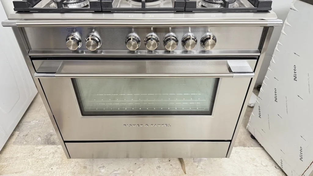 Stainless Fisher and Paykel gas range with oven and control knobs.