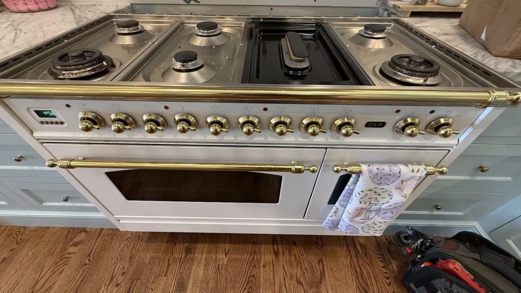 Stainless ILVE gas range with multiple burners and gold trim.