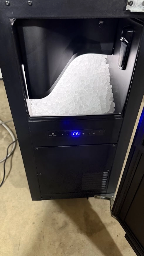 Black Marvel ice machine with open ice bin and fresh ice.