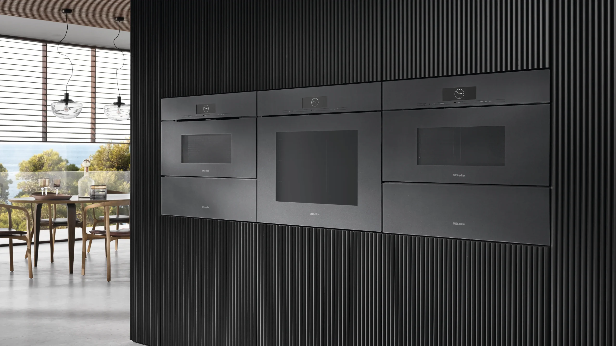 Miele appliances integrated into dark kitchen cabinets.