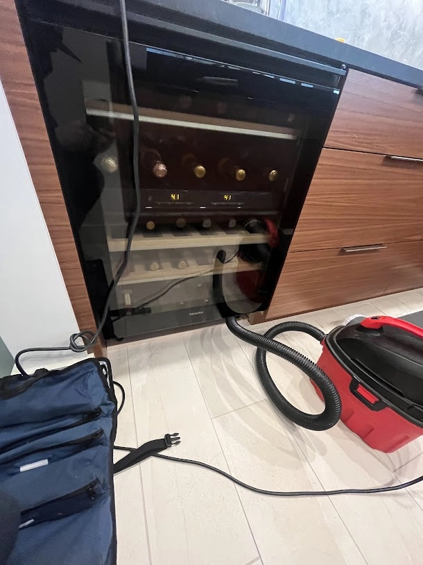 Built in Miele wine cooler with door open and service equipment nearby.
