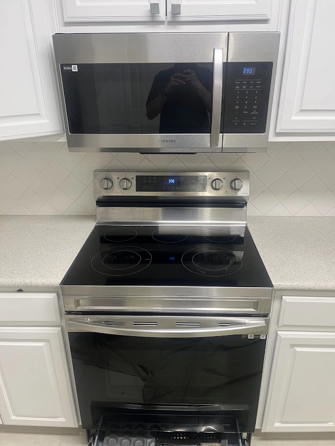 Samsung electric range with microwave mounted above it.