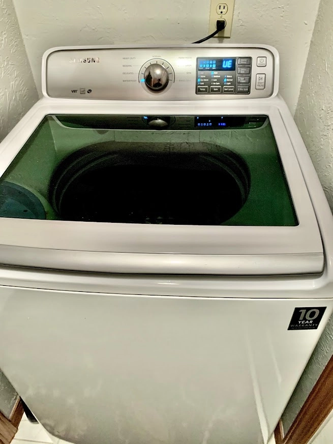 White Samsung top load washer with glass lid.
