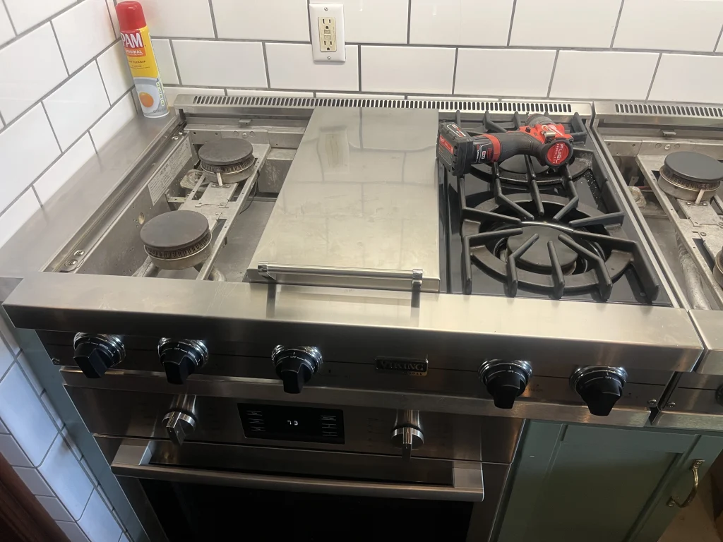 Stainless Viking range with gas burners and service tools on the cooktop.