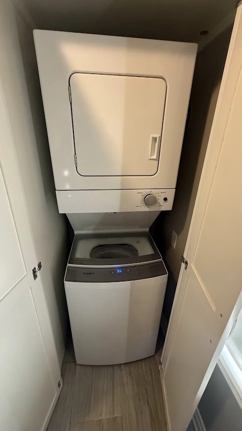 White Whirlpool dryer stacked above a top load washer in a laundry closet.