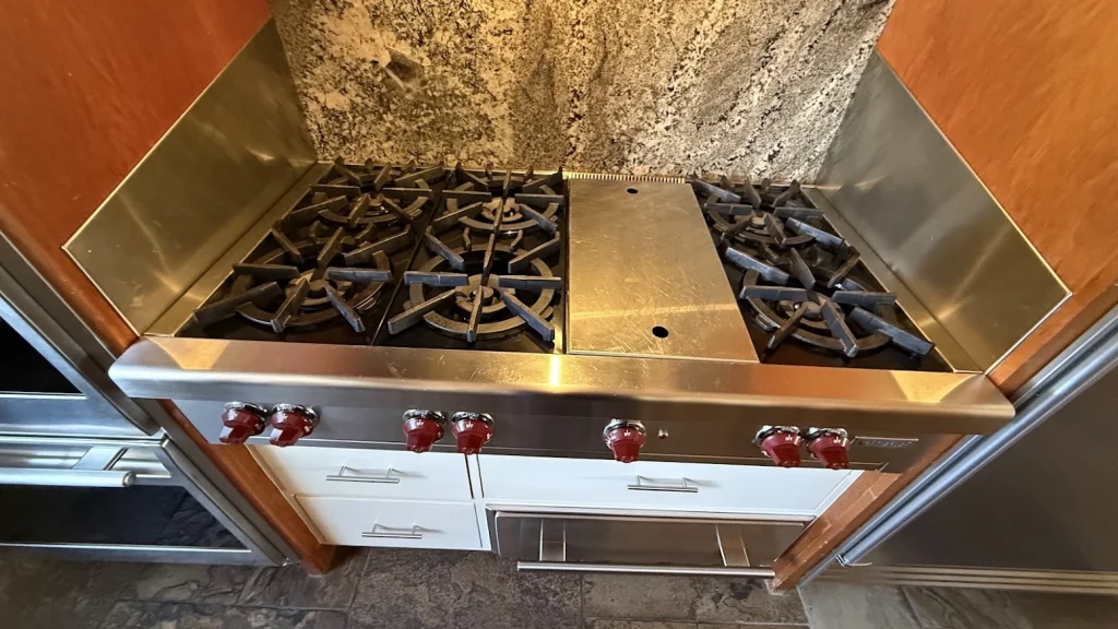 Stainless Wolf gas cooktop with red knobs and center griddle.