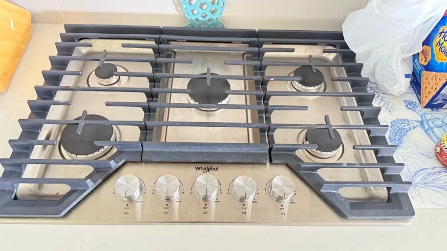 Whirlpool gas cooktop with five burners and front control knobs, seen from above