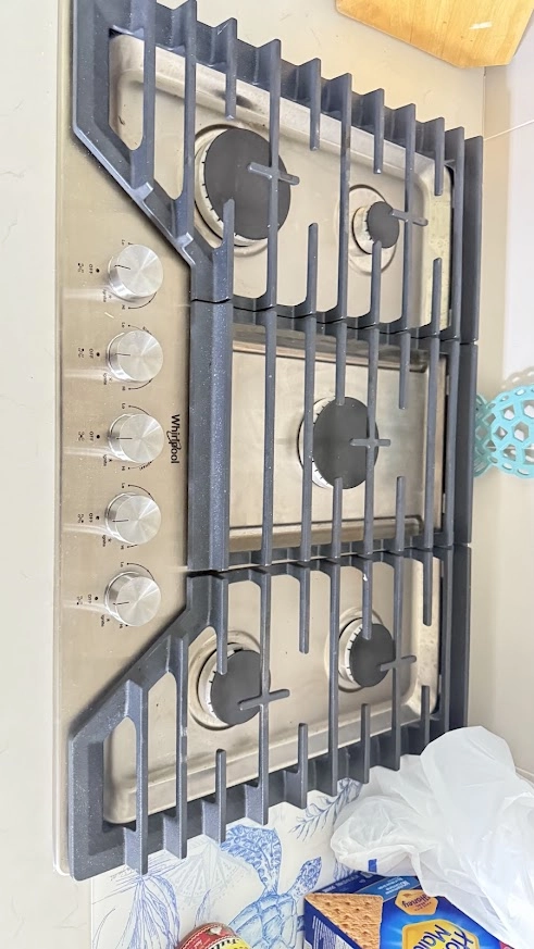 Whirlpool gas cooktop with grates removed and burners exposed.
