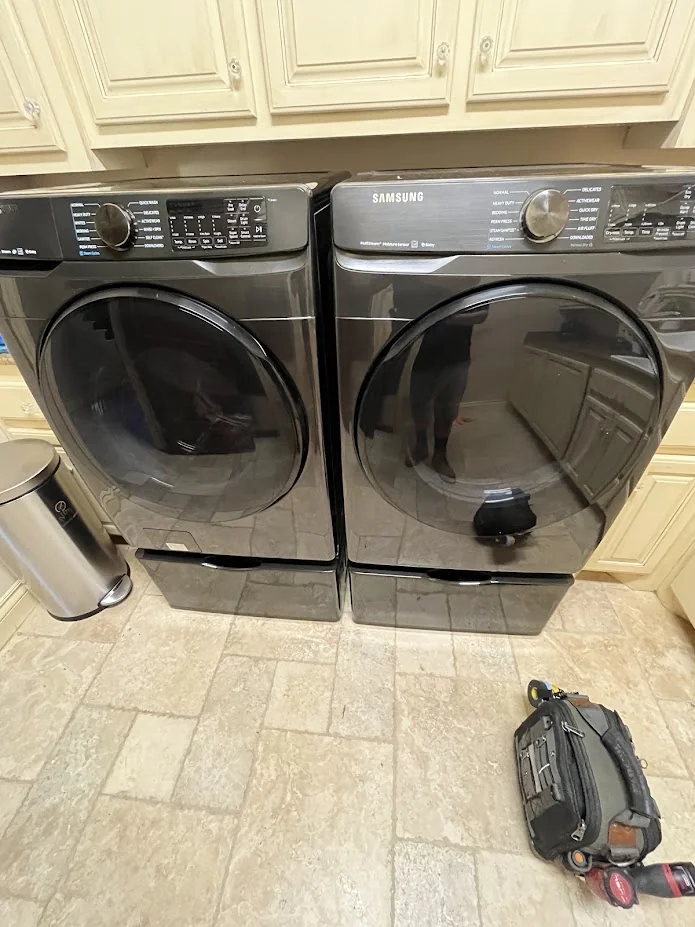 Black front-load washer and dryer in a tiled laundry room.