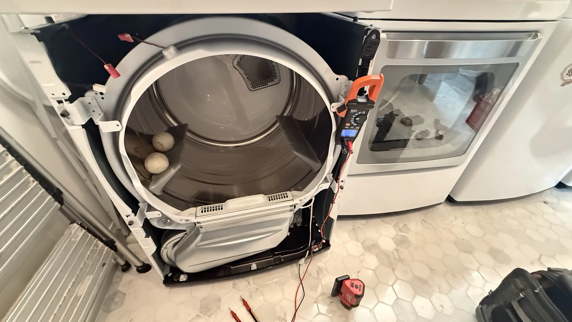Front-load dryer with the front panel removed, exposing the drum and internal parts.