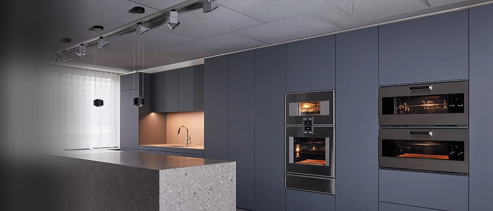 Gaggenau wall ovens built into dark blue kitchen cabinetry
