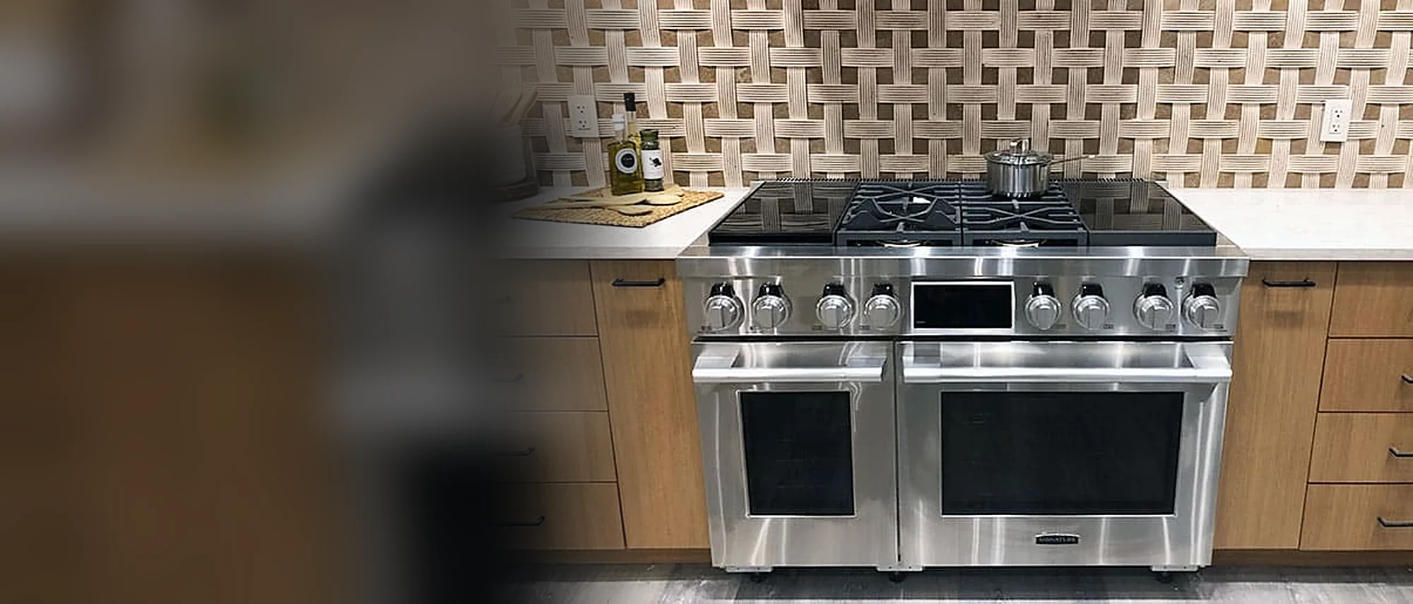 Stainless Hestan dual-fuel range under a woven tile backsplash