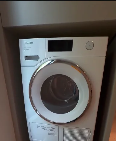 White Miele T1 heat pump dryer installed in a laundry alcove