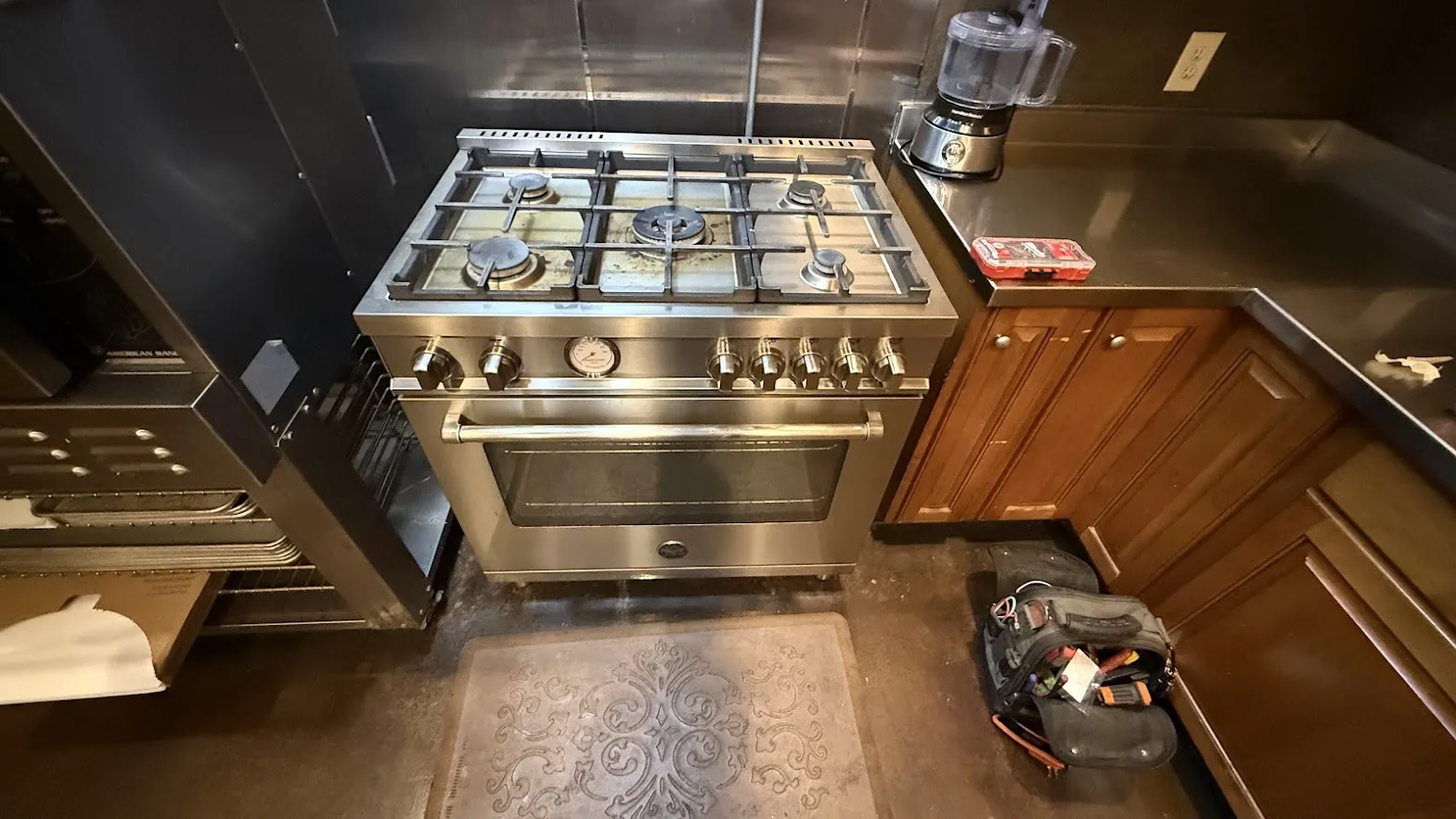 Stainless steel Bertazzoni gas range and oven with a tool bag on the kitchen floor