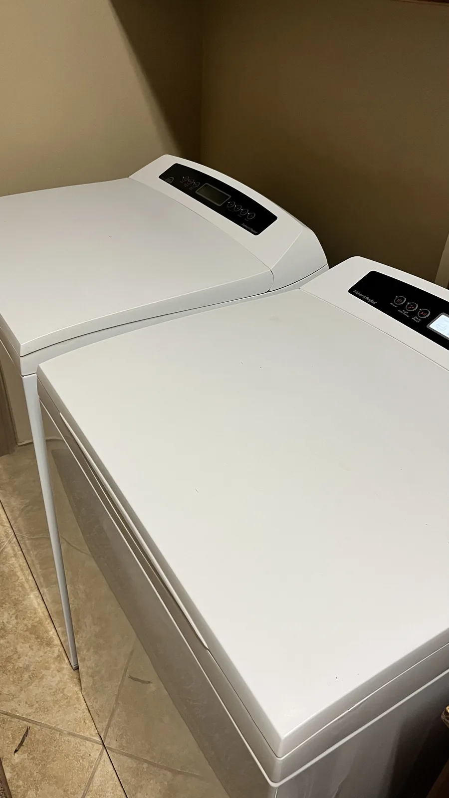 White Fisher and Paykel top-load washer and matching dryer in a laundry room