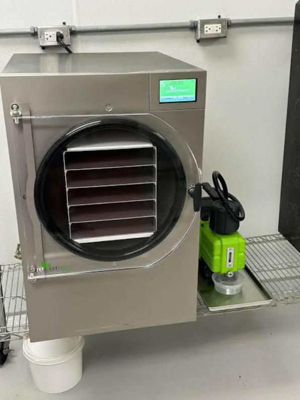 Harvest Right freeze dryer with an open tray chamber and a vacuum pump beside it
