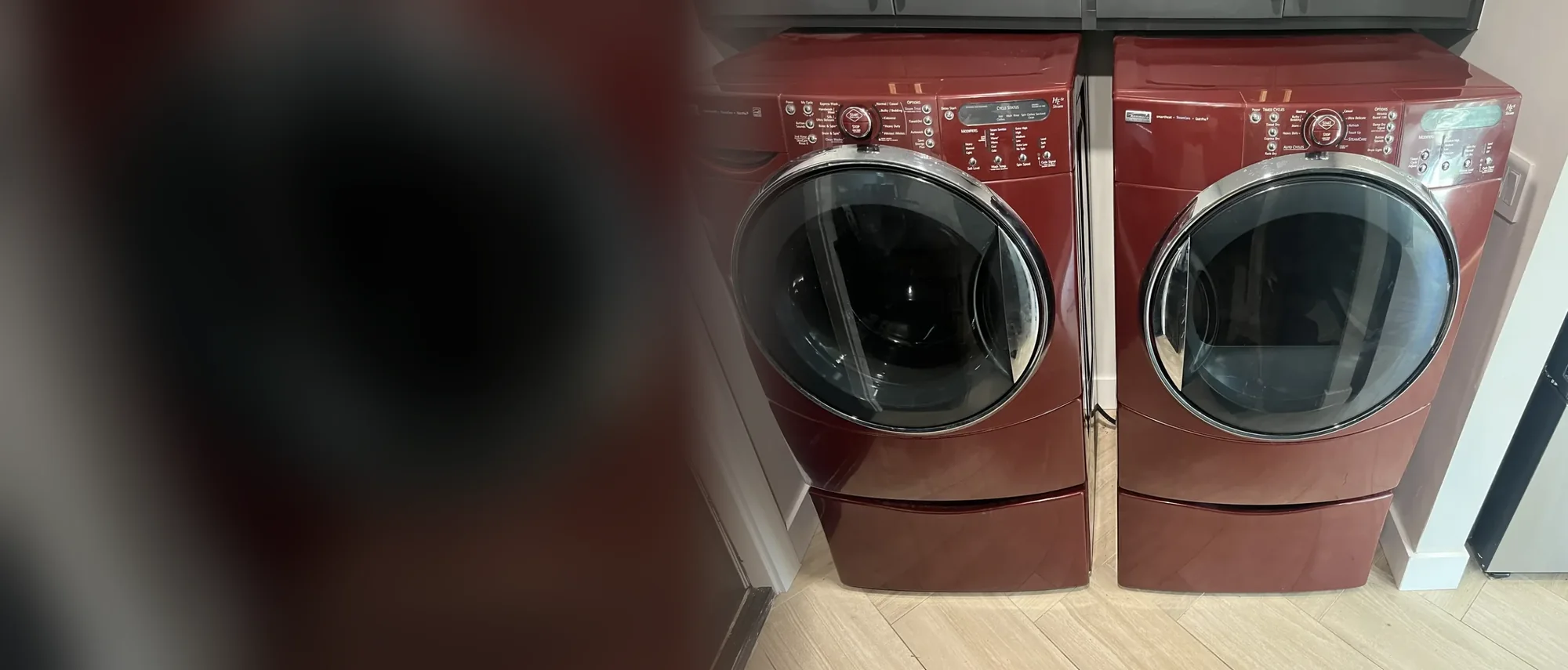Red front-load washer and dryer pair on pedestals