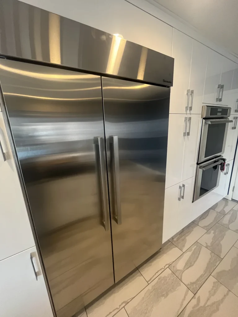 Thermador stainless steel built-in refrigerator beside a double wall oven
