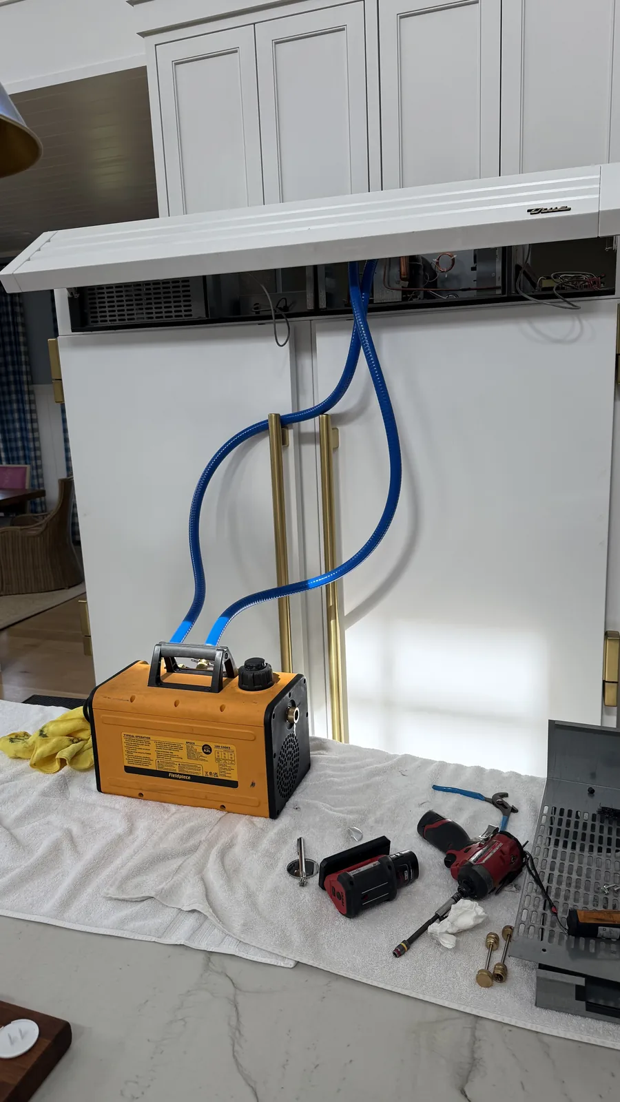 True built-in refrigerator with its upper service panel open and service tools on a protective cloth