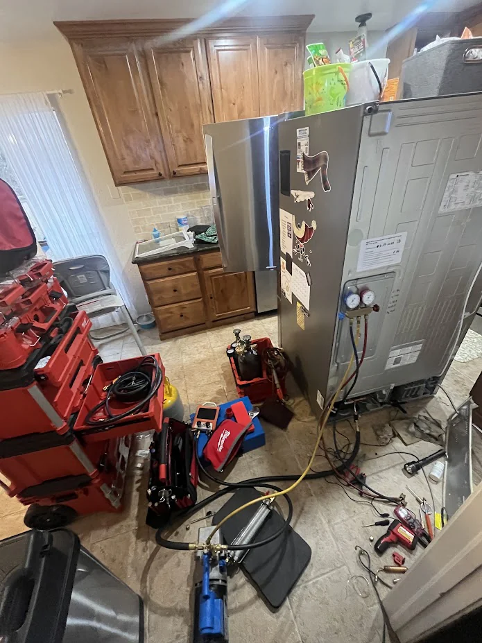 Nichols Hills Appliance Repair 5 Rear of a built-in refrigerator opened for diagnostics with tools and gauges nearby.