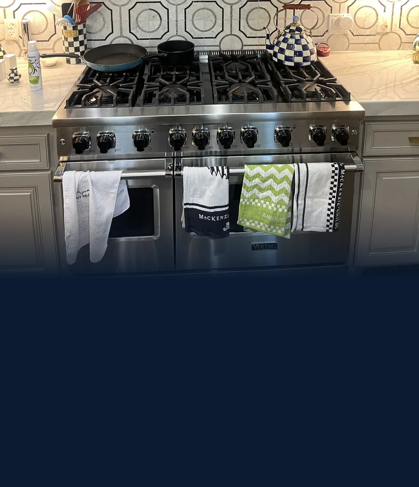 Stainless steel Viking gas range and oven installed beneath a kitchen hood