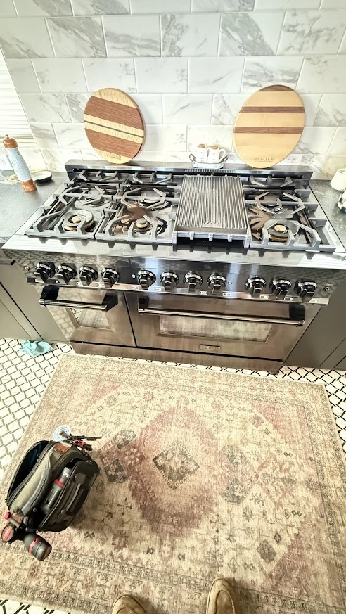 Stainless ZLINE gas range with hood and service tools nearby.